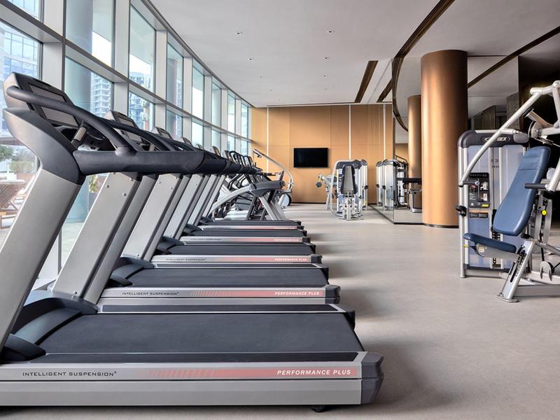 Moderní posilovna s běžeckými pásy a dalšími cvičebními stroji v hotelu.