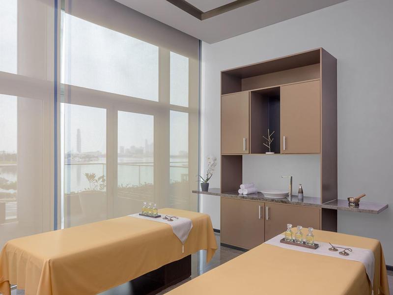 Světelná wellness místnost se dvěma masážními lehátky a velkými okny.