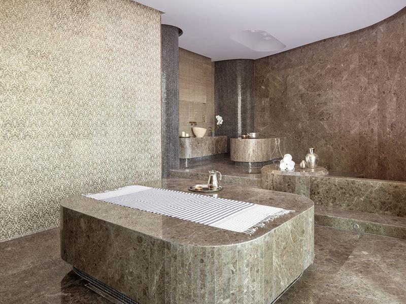 Luxusní koupelna s velkou centrální vanou a moderním vybavením v přírodních tónech.