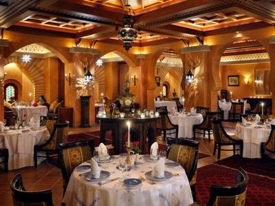 Elegant en warm verlicht restaurant met ronde gedekte tafels en houten lambrisering.