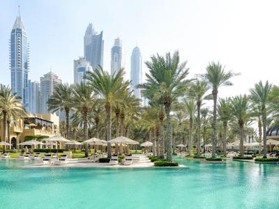 Grande piscina con palme e skyline moderna sullo sfondo