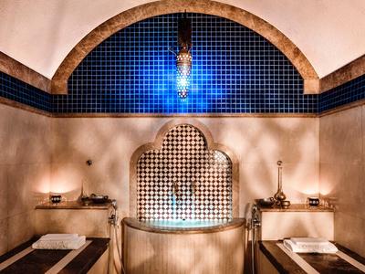 Elegante wellnessruimte met mozaïektegels, twee ligstoelen en warme verlichting.