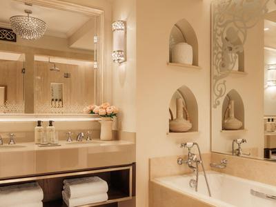 Elegante badkamer met groot bad, handdoekenrek en warme verlichting.