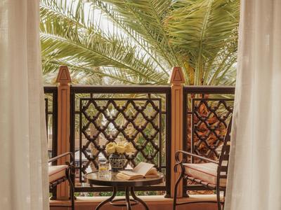 Balkon met twee houten stoelen en een kleine ronde tafel voor palmbomen