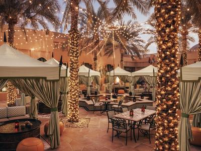 Terrazza dell'hotel serale con palme illuminate e aree salotto coperte all'aperto.