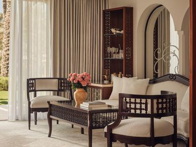 Elegante zithoek met tapijt, houten meubels, bloemendecoratie en uitzicht op de tuin.