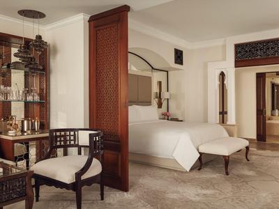 Lichte hotelkamer met tweepersoonsbed, houten scheidingswand en twee gestoffeerde stoelen