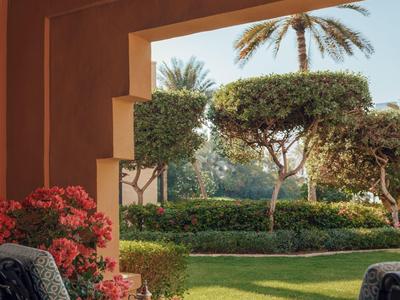 Gezellig zitgedeelte in een hoteltuin met uitzicht op groene planten en palmbomen.