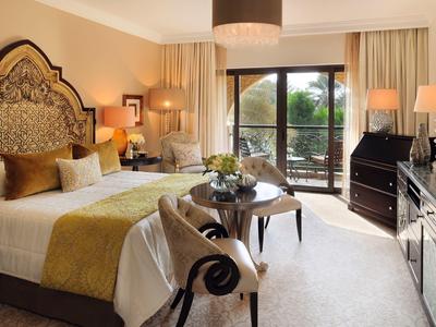 Elegant hotelkamer met grote ramen, tweepersoonsbed en gezellige zithoek.