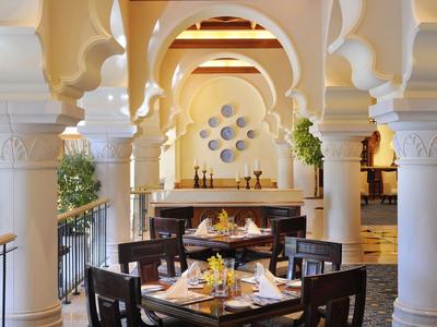 Elegant restaurant met decoratieve zuilen en warm licht, tafels gedekt met bloemen.