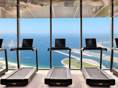 Fitnessruimte met loopbanden voor grote ramen met uitzicht op de zee