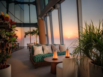 Moderne lounge met zonsondergang, ingericht met planten en comfortabele zitplaatsen.