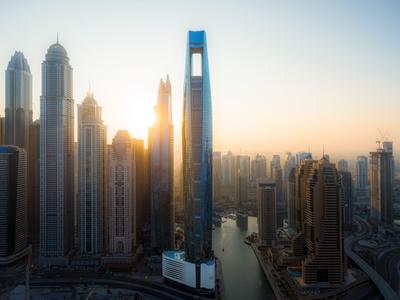 Uitzicht op een moderne stad met wolkenkrabbers en een rivier bij zonsondergang.