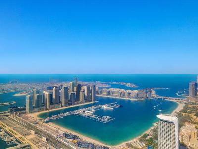 Uitzicht op een moderne kuststad met haven en wolkenkrabbers bij helder weer.