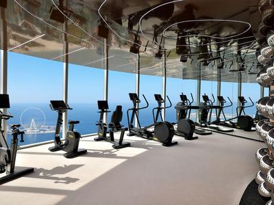 Moderne sportschool met hometrainers en halters voor grote ramen met uitzicht op zee.