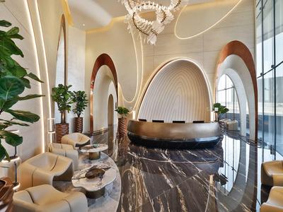 Moderne hotel lobby met marmeren vloer, afgeronde receptiebalie en grote ramen.