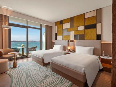 Moderní hotelový pokoj se dvěma jednolůžky, velkým oknem a výhledem na moře