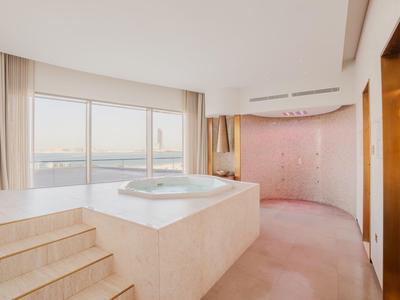Elegantes Hotelzimmer mit Whirlpool, großem Fenster und Blick auf Wasser und Stadt.