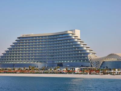 Modernes, terrassenförmiges Hotel am Wasser mit klarem blauem Himmel.