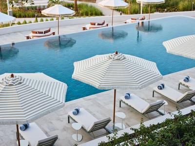 Moderner Poolbereich mit weißen Sonnenschirmen und Liegestühlen neben klarem Wasser