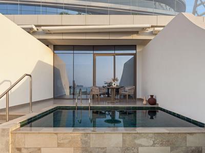 Schwimmbad auf einer Terrasse mit Glaswand und moderner Architektur im Hintergrund.