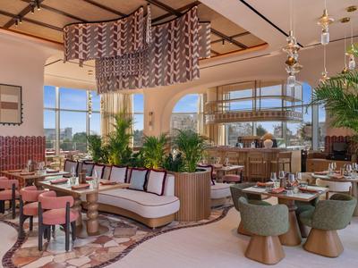 Elegantní hotelová restaurace se stylovými posezeními a velkými okny s výhledem ven.