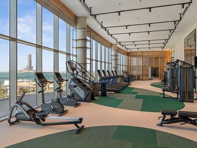 Helle Fitnessstudio mit großen Fenstern und Blick auf das Meer, ausgestattet mit modernen Cardio-Geräten.