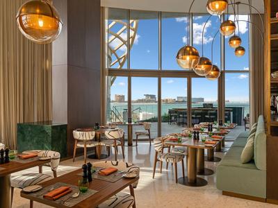 Helles, modernes Restaurant mit großen Fenstern, hängenden Kugelleuchten und stilvollen Tischen.