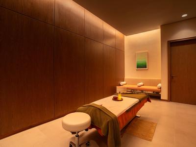 Ruhiger Spa-Raum mit Massagebank, warmen Holzwänden und sanfter Beleuchtung.