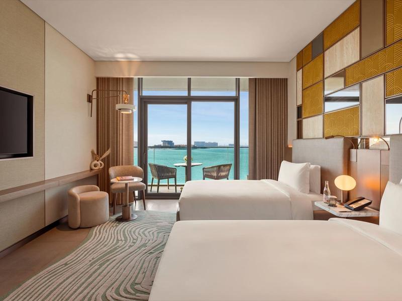 Moderní hotelový pokoj se dvěma postelemi a výhledem na moře přes velká okna