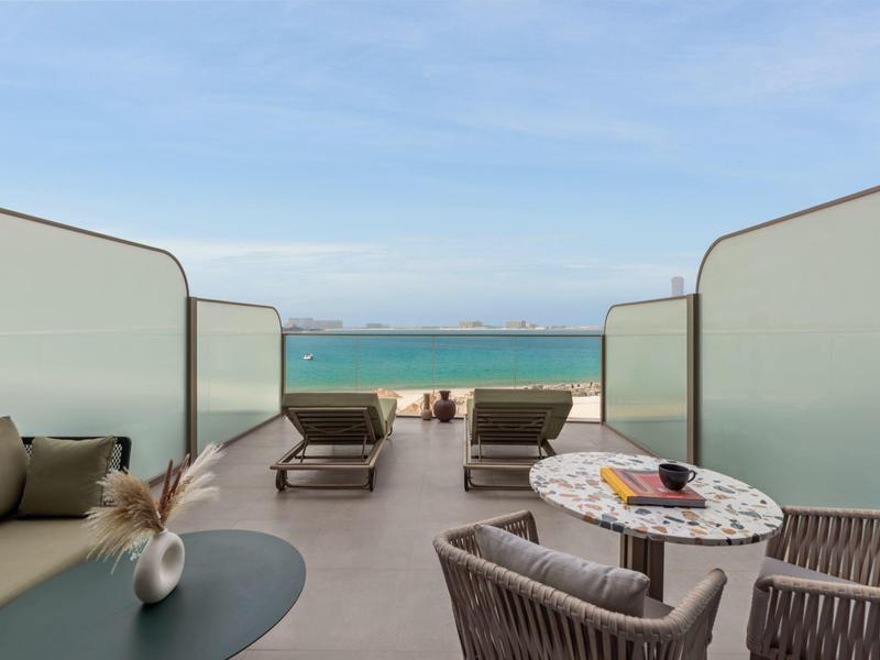 Moderní venkovní posezení s výhledem na moře a jasnou modrou oblohu.