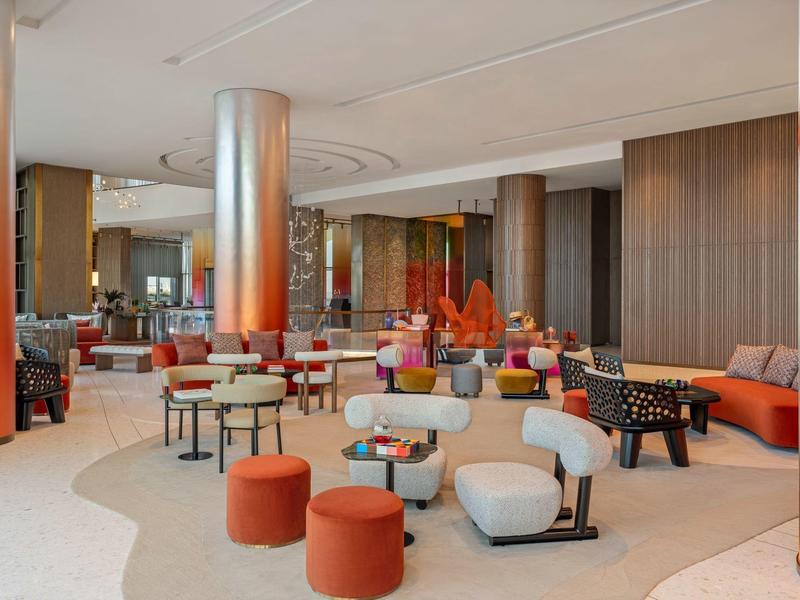 Moderní hotelová lounge s různými sedacími místy a teplými barvami.