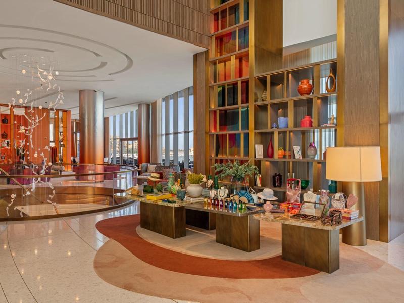 Moderní hotelová lobby s vysokým regálem na knihy a elegantním posezením.