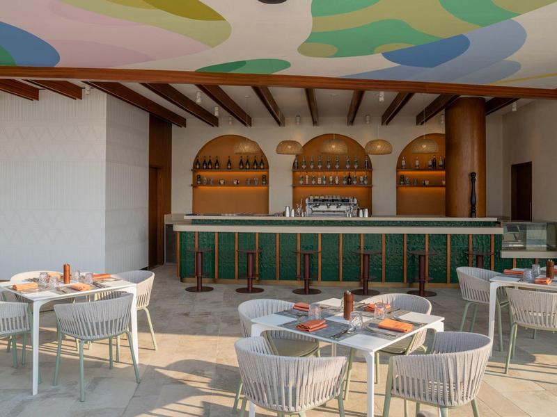 Moderní venkovní prostor hotelu s barem a posezením pod barevným stropem.