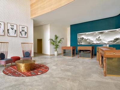 Heller Hotel-Loungebereich mit modernen Stühlen, Tischen und dekorativer Wandgestaltung.