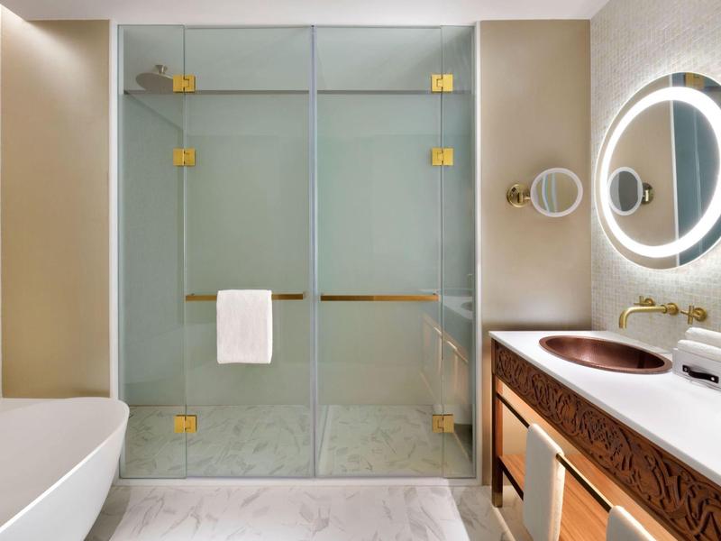 Modernes Badezimmer mit begehbarer Dusche, Badewanne und Doppelwaschbecken mit beleuchtetem Spiegel.