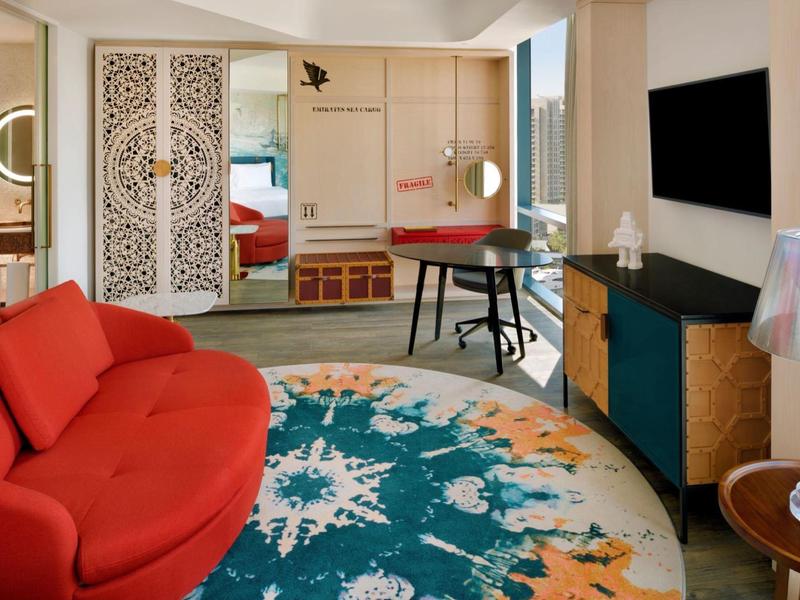 Modernes Wohnzimmer mit rotem Sofa, rundem Teppich und Fernseher an der Wand.