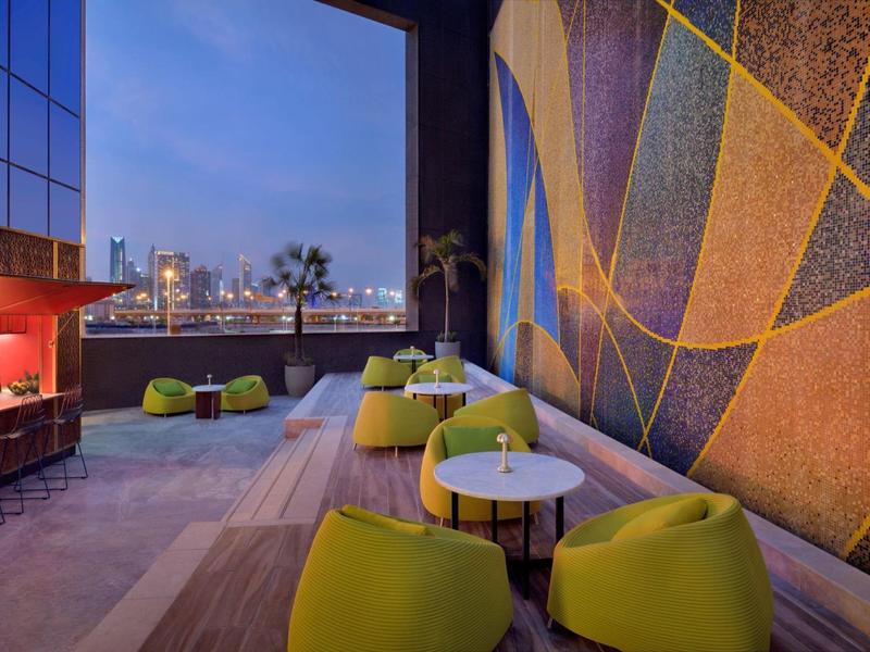 Moderner Lounge-Bereich mit grünen Sitzmöbeln und großem Fenster mit Blick auf die Stadt bei Sonnenuntergang.