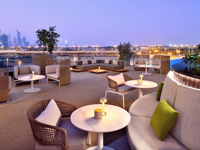 Dachterrasse mit Sitzbereichen und Stadtblick bei Dämmerung.