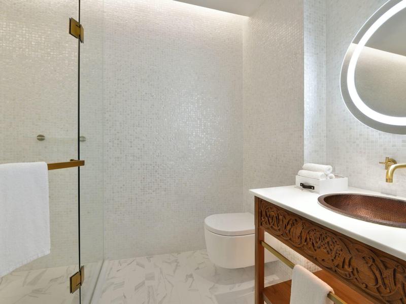 Modernes Badezimmer mit Glasdusche, WC und Holzwaschtisch mit rundem Spiegel.