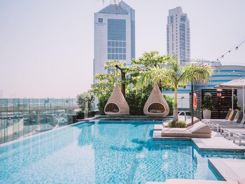 Dachpool mit modernen Liegestühlen und Stadtblick bei klarem Himmel