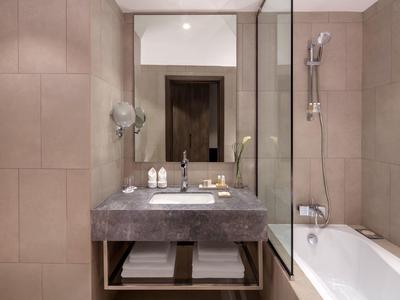 Moderní koupelna se umyvadlem, velkou zrcadlovou stěnou a vanou se skleněnou přepážkou.