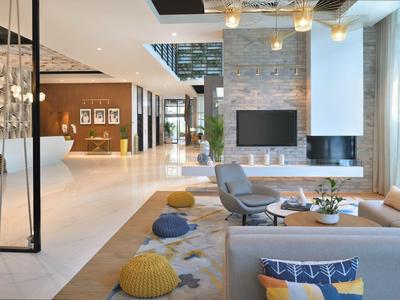 Helles Loungehotel mit modernen Möbeln, Kamin und Teppich mit bunten Kissen.