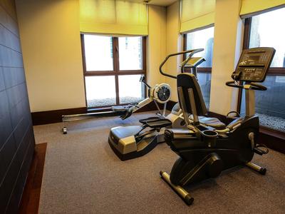 Kleines Fitnessstudio mit Crosstrainern vor großen Fenstern und Teppichboden.