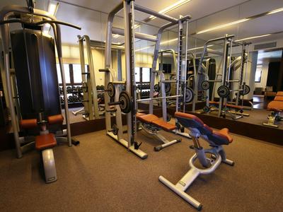 Moderner Fitnessraum mit verschiedenen Trainingsgeräten und großen Spiegeln