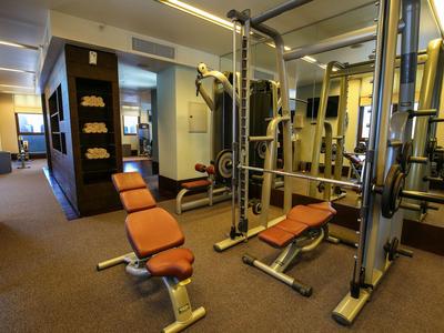 Helles Fitnessstudio mit Hantelbänken, Spiegelwand und Handtuchregalen in einem Hotel.