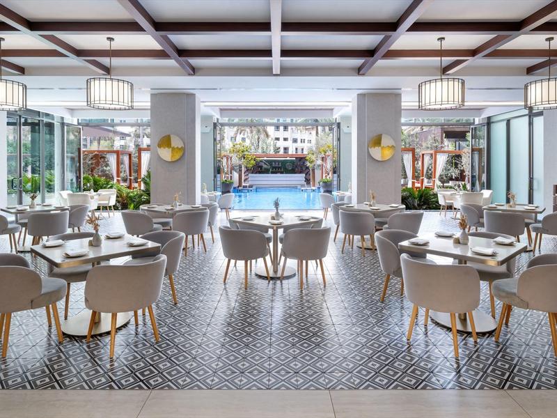 Modern restaurant overlooking a pool and cityscape in the background