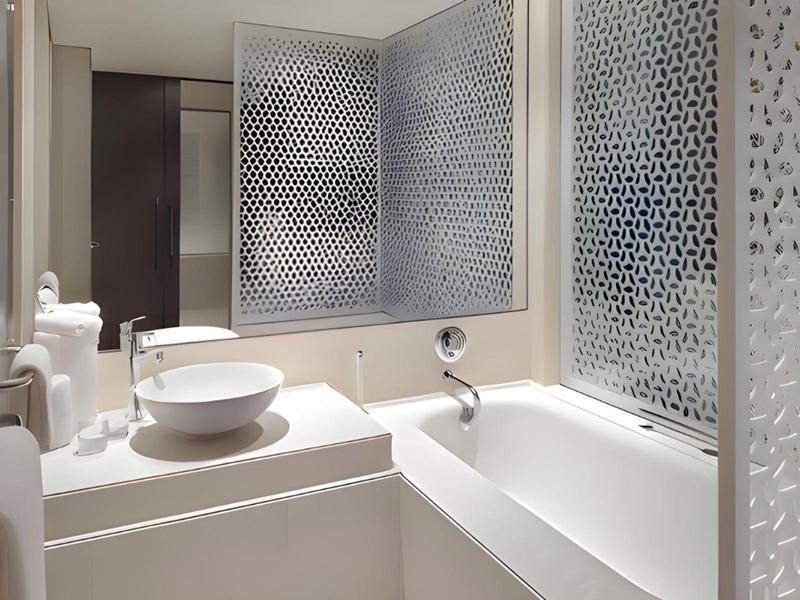 Bright bathroom with white bathtub, sink, and decorative patterned glass walls.