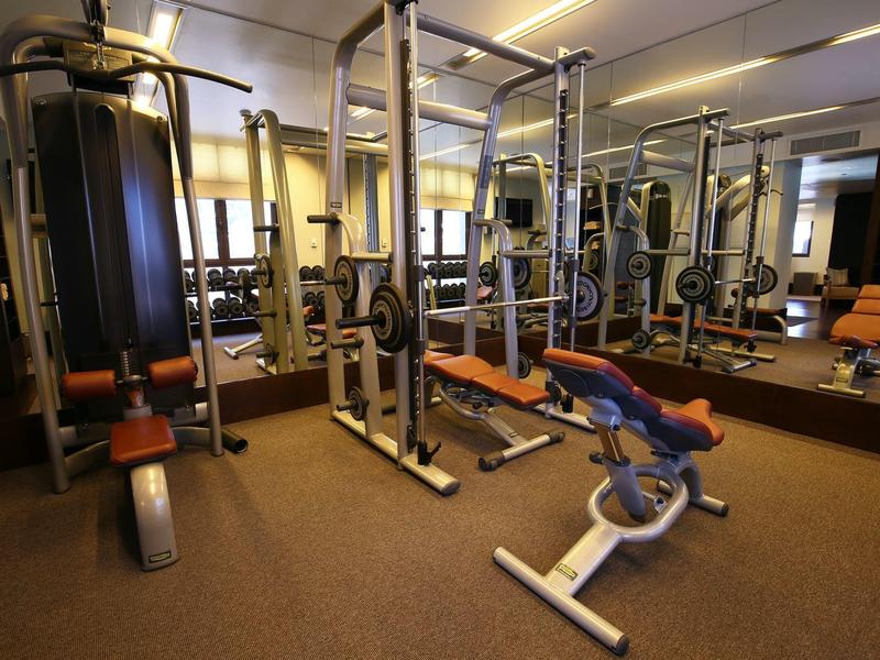 A well-equipped gym with workout machines and mirrors on the wall.