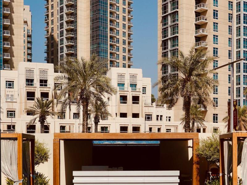 Modern outdoor pool with lounge benches and high-rise buildings in the background on a sunny day.
